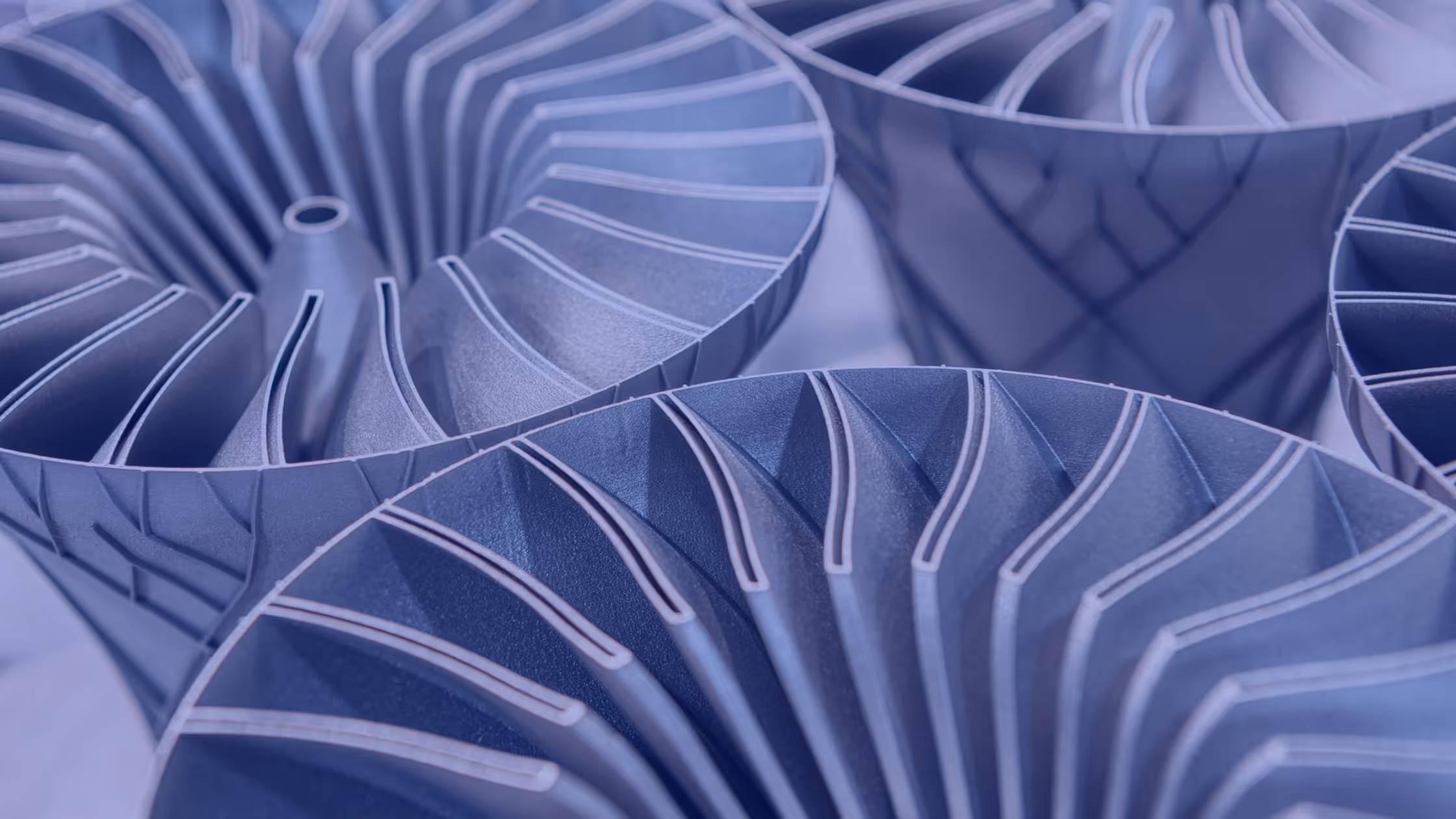 A young woman working in a machine shop. She is looking directly towards the camera, and is surrounded by men.