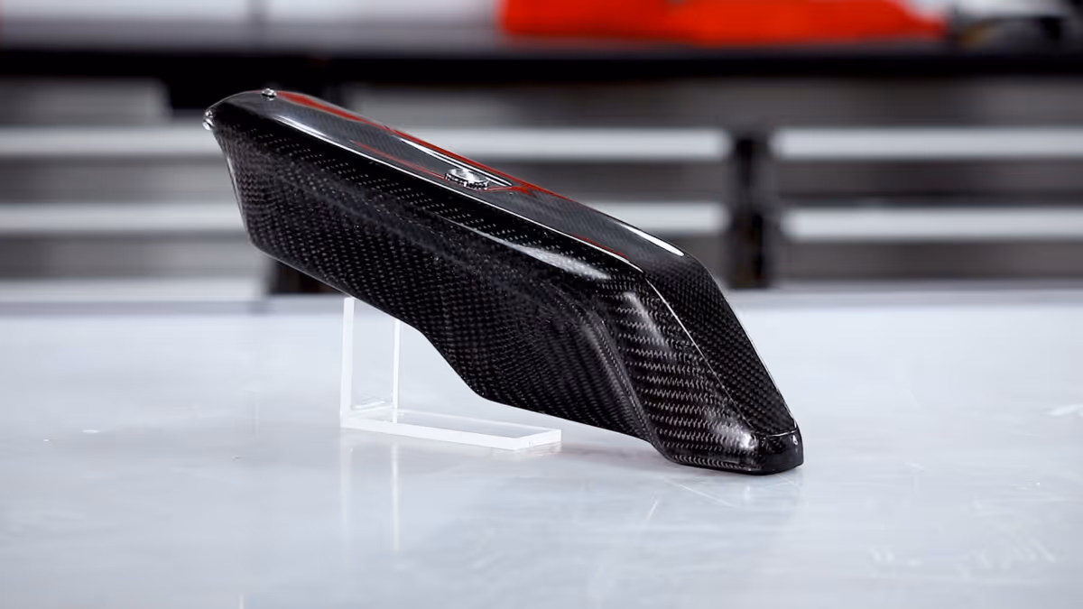 A young woman working in a machine shop. She is looking directly towards the camera, and is surrounded by men.