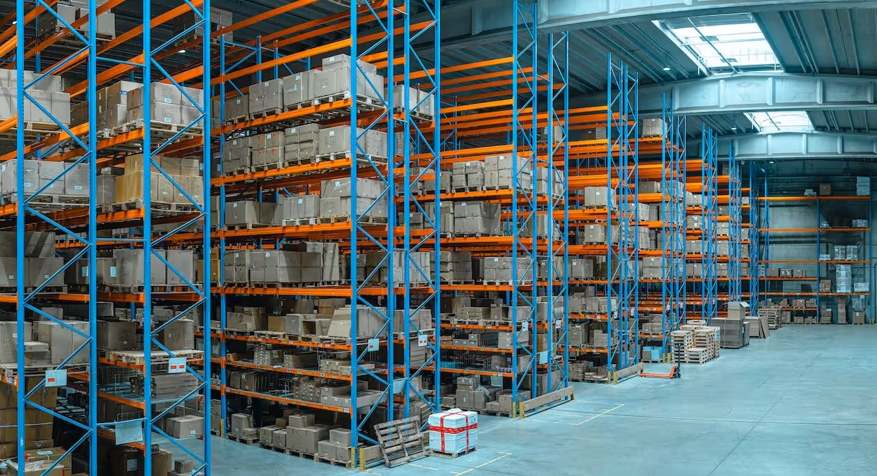 A young woman working in a machine shop. She is looking directly towards the camera, and is surrounded by men.