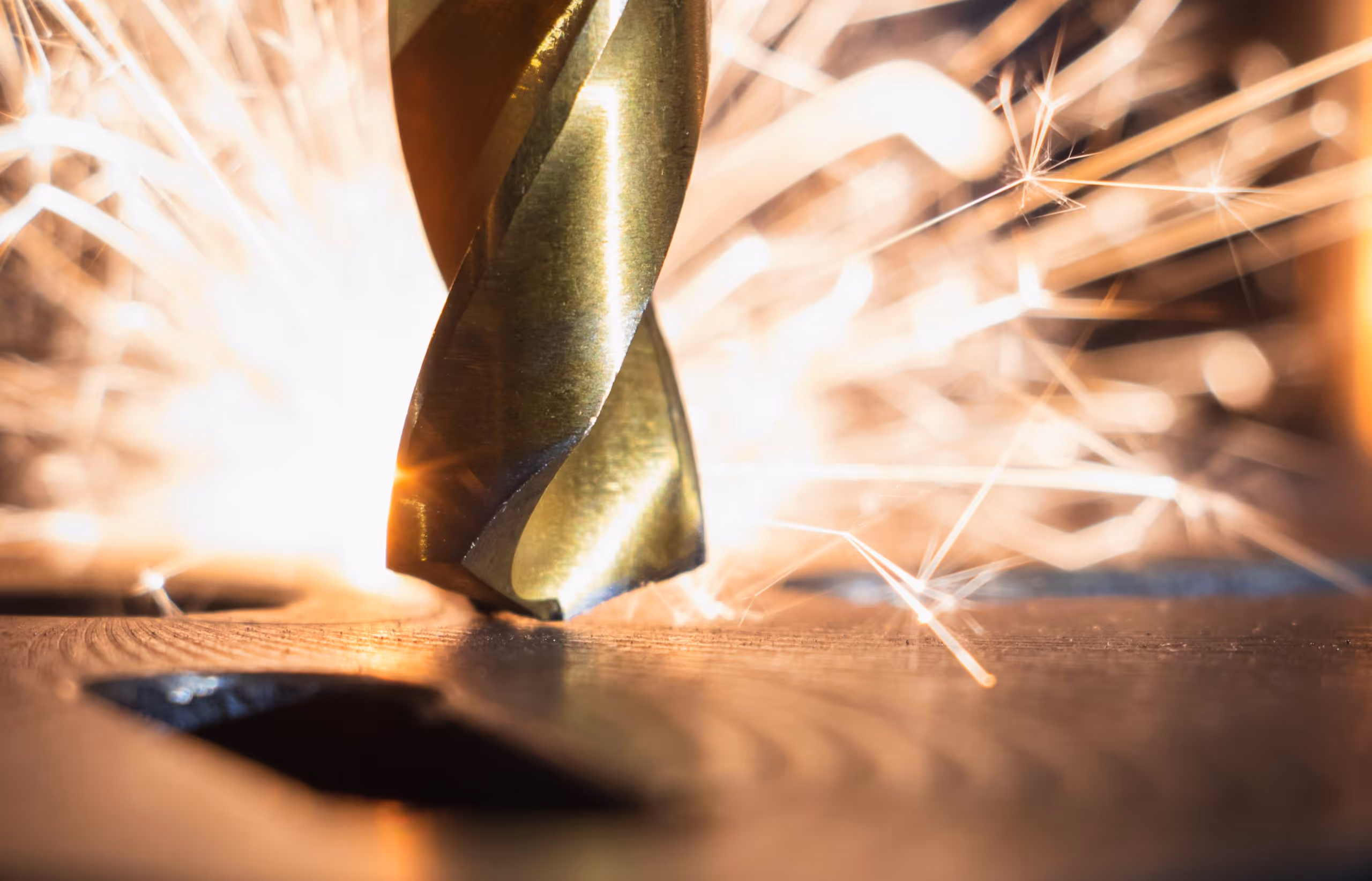 A young woman working in a machine shop. She is looking directly towards the camera, and is surrounded by men.