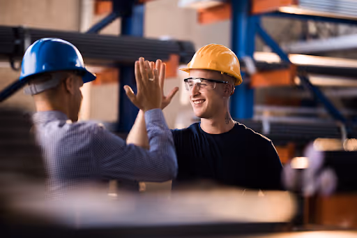 Two men in hard hats high fiving
