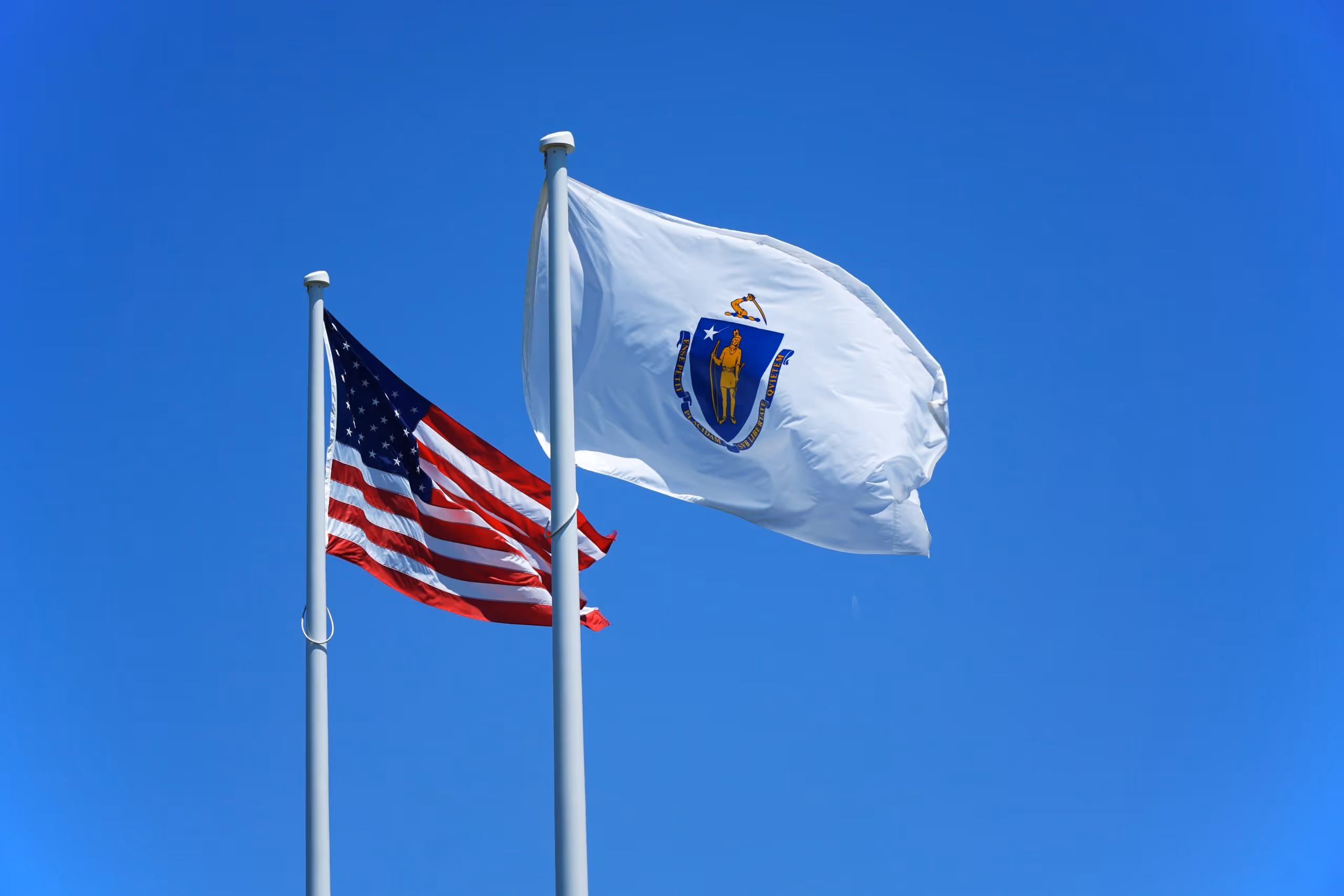 A young woman working in a machine shop. She is looking directly towards the camera, and is surrounded by men.