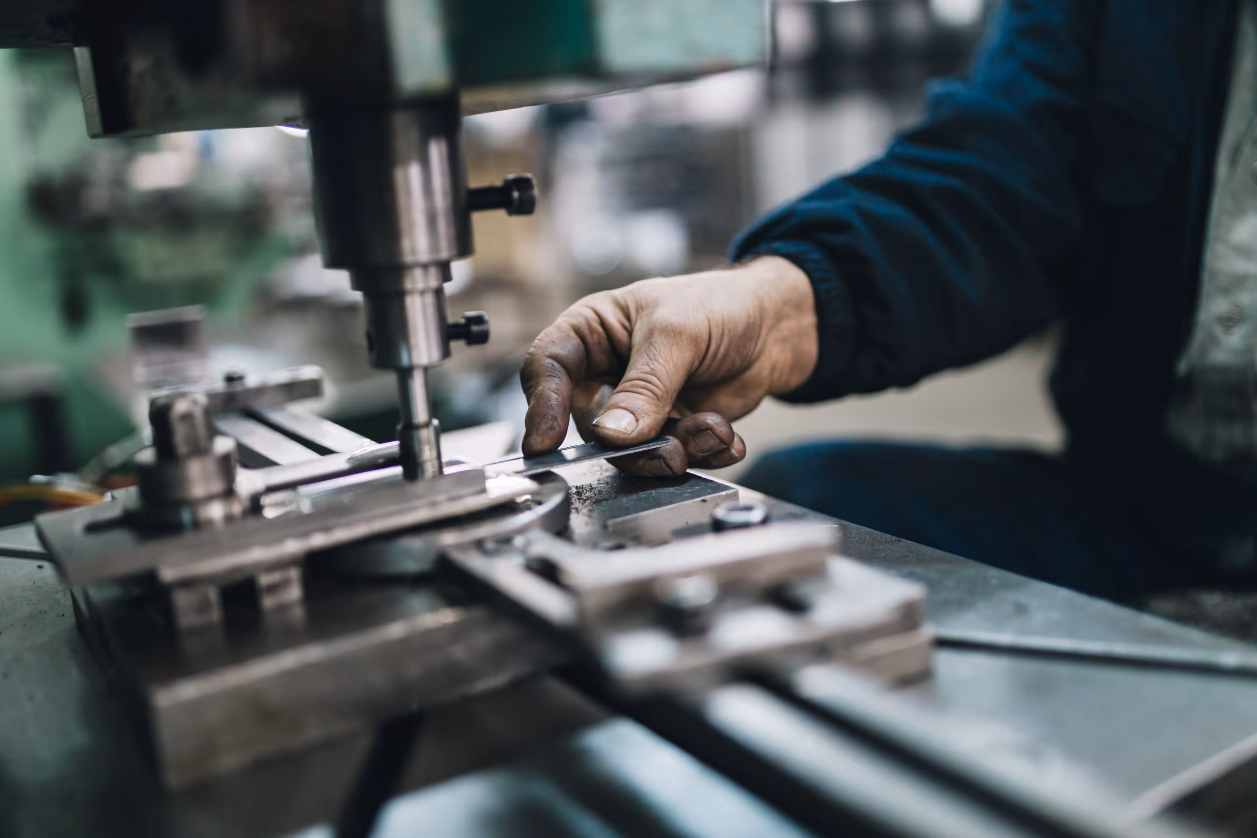A young woman working in a machine shop. She is looking directly towards the camera, and is surrounded by men.