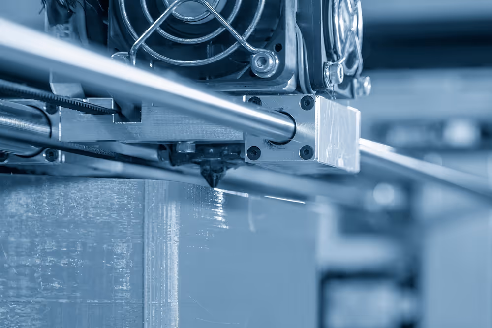 A young woman working in a machine shop. She is looking directly towards the camera, and is surrounded by men.