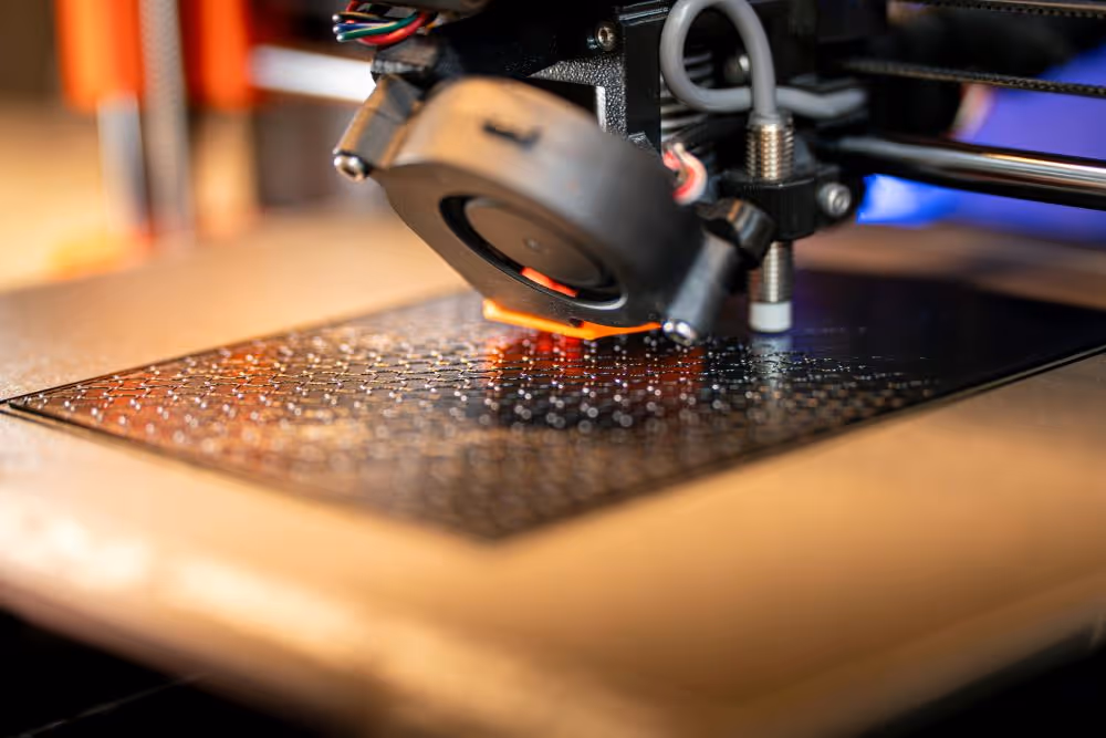 A young woman working in a machine shop. She is looking directly towards the camera, and is surrounded by men.