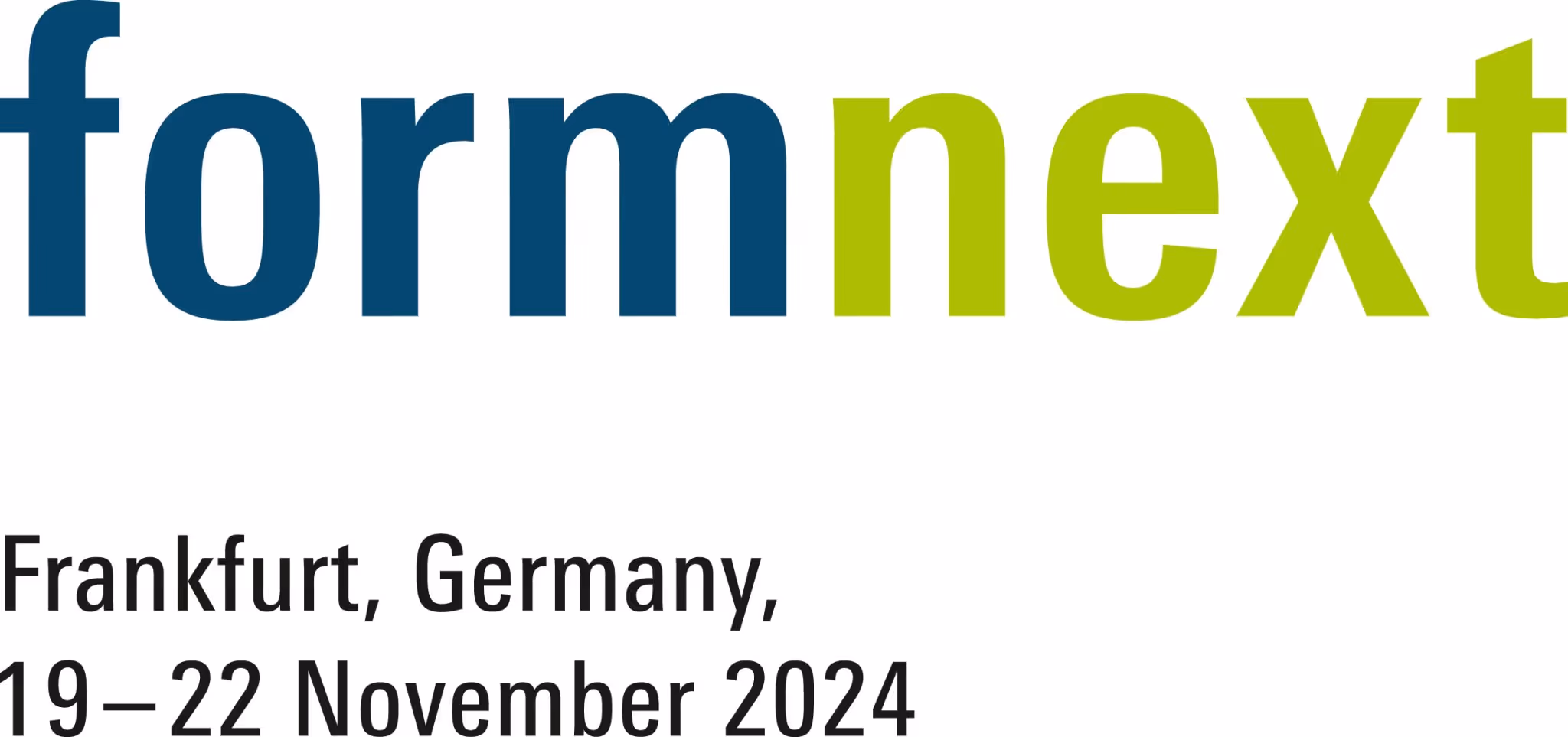 A young woman working in a machine shop. She is looking directly towards the camera, and is surrounded by men.