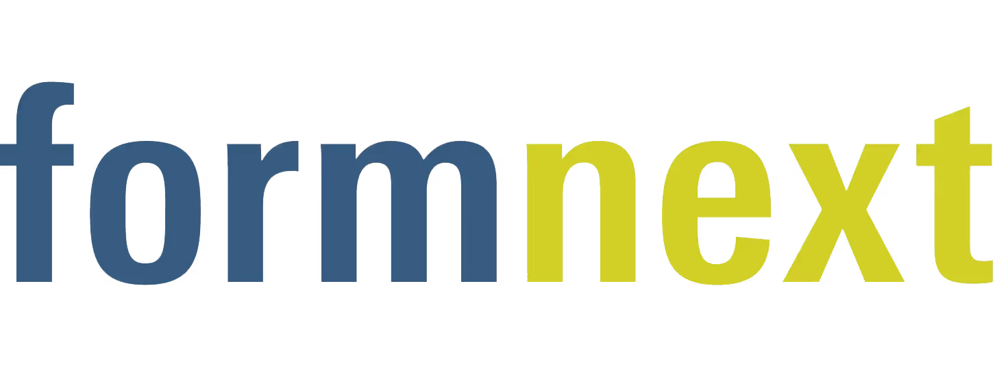 A young woman working in a machine shop. She is looking directly towards the camera, and is surrounded by men.