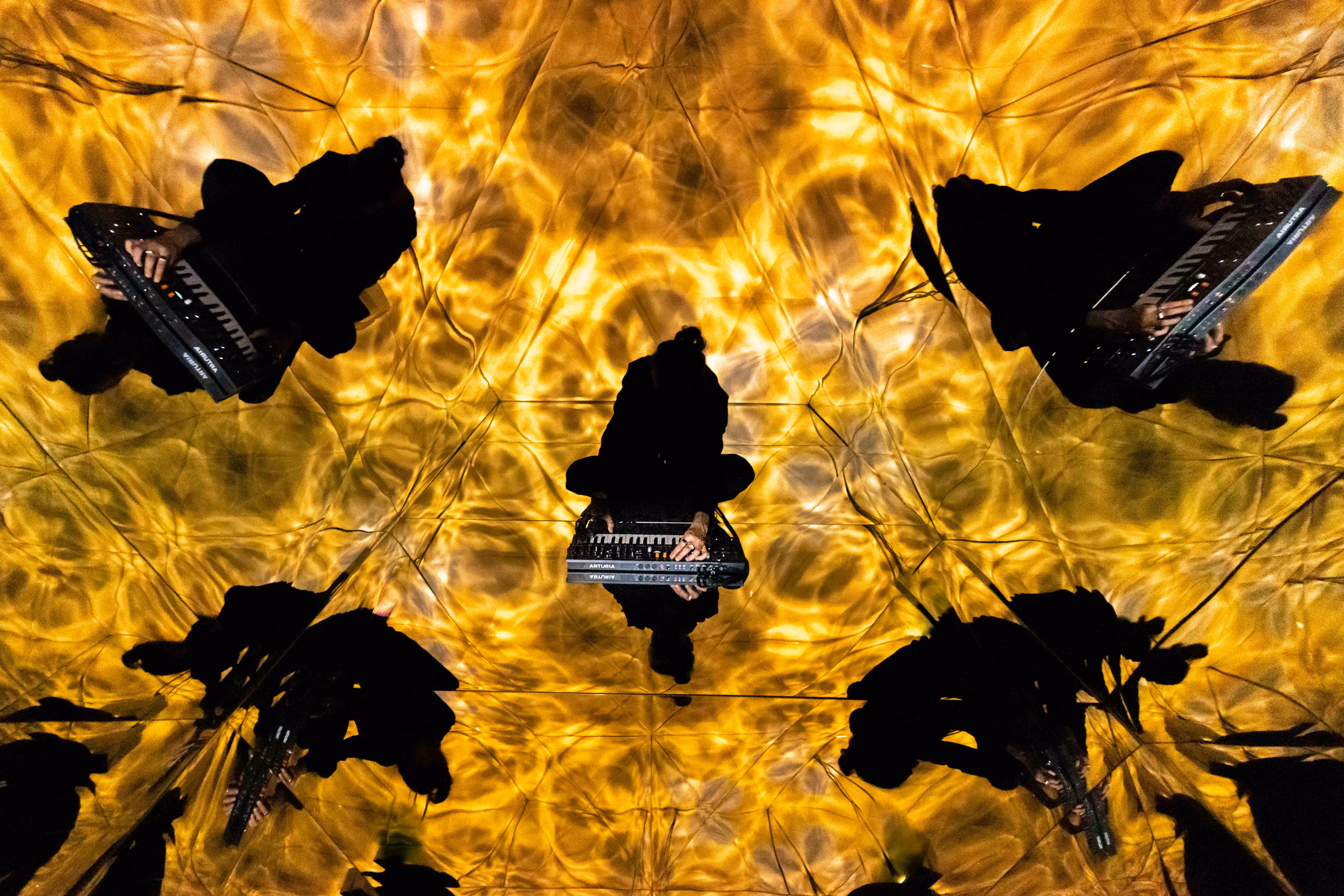 Musicien jouant d'un synthétiseur entouré de reflets réfléchissants et de lumière dorée dans un film de marque créatif.
