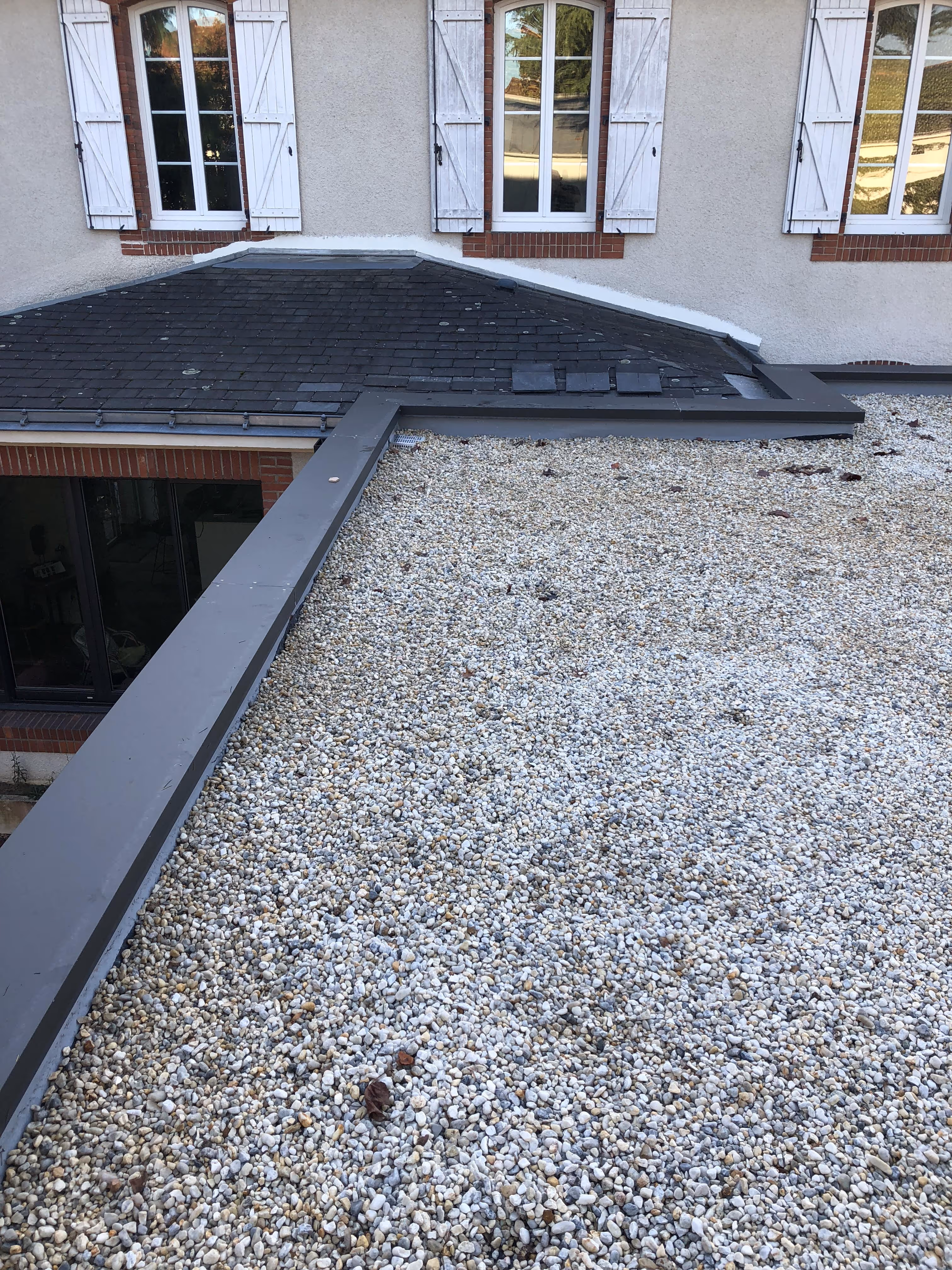Toiture terrasse en gravillons avec relevés d’étanchéité et raccords sur toiture en ardoise à Nantes, garantissant une protection durable contre les infiltrations.
