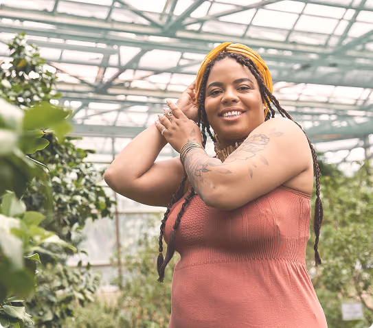 A happy woman in a beautiful green background of plants.