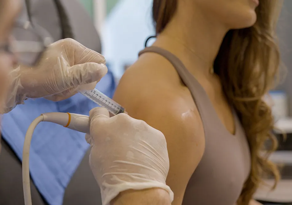 Medical professional administering an ultrasound-guided injection to a patient's shoulder in a clinical setting