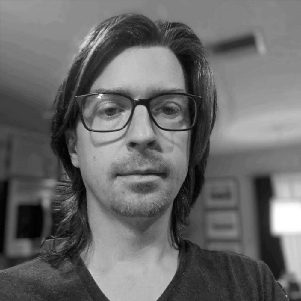 Alex, Cytonics team member, with shoulder-length hair and rectangular glasses