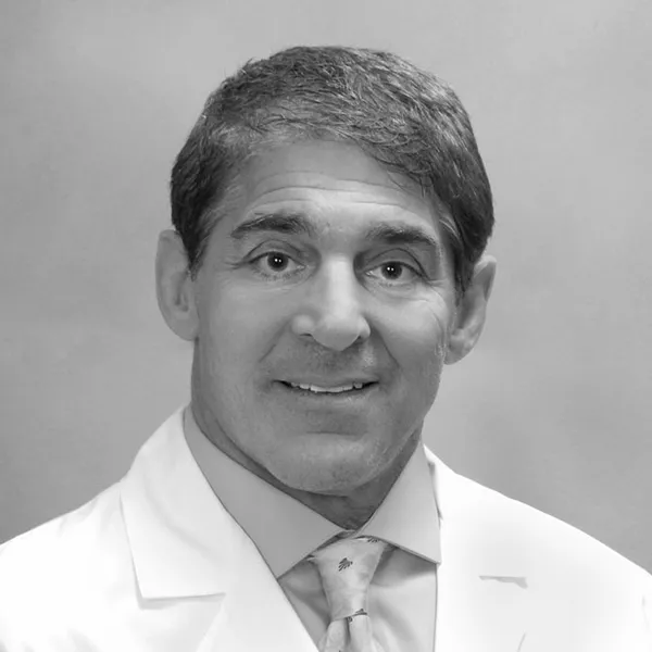 Gaetano Scuderi, Cytonics Founder, smiling in a white lab coat with a patterned tie (black and white)