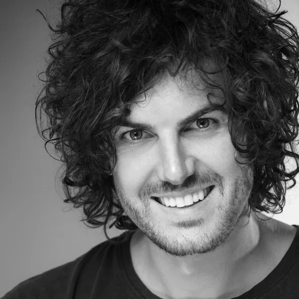 Michael Hartwich, Cytonics team member, smiling broadly with curly hair in a dark t-shirt