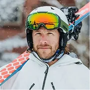 Man wearing ski goggles and helmet in snowy conditions