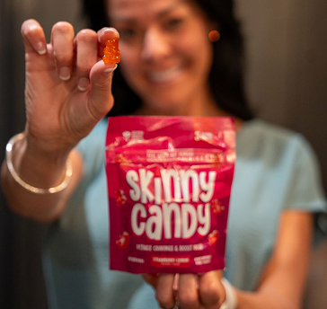 A woman holding a bag of skinny candy.