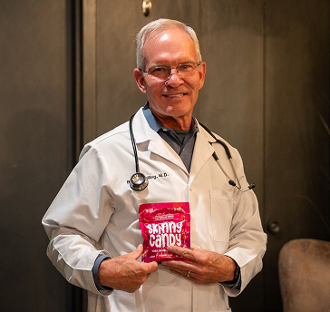 A man in a white lab coat holding a book.