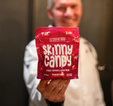 A man holding a bag of skinny candy.