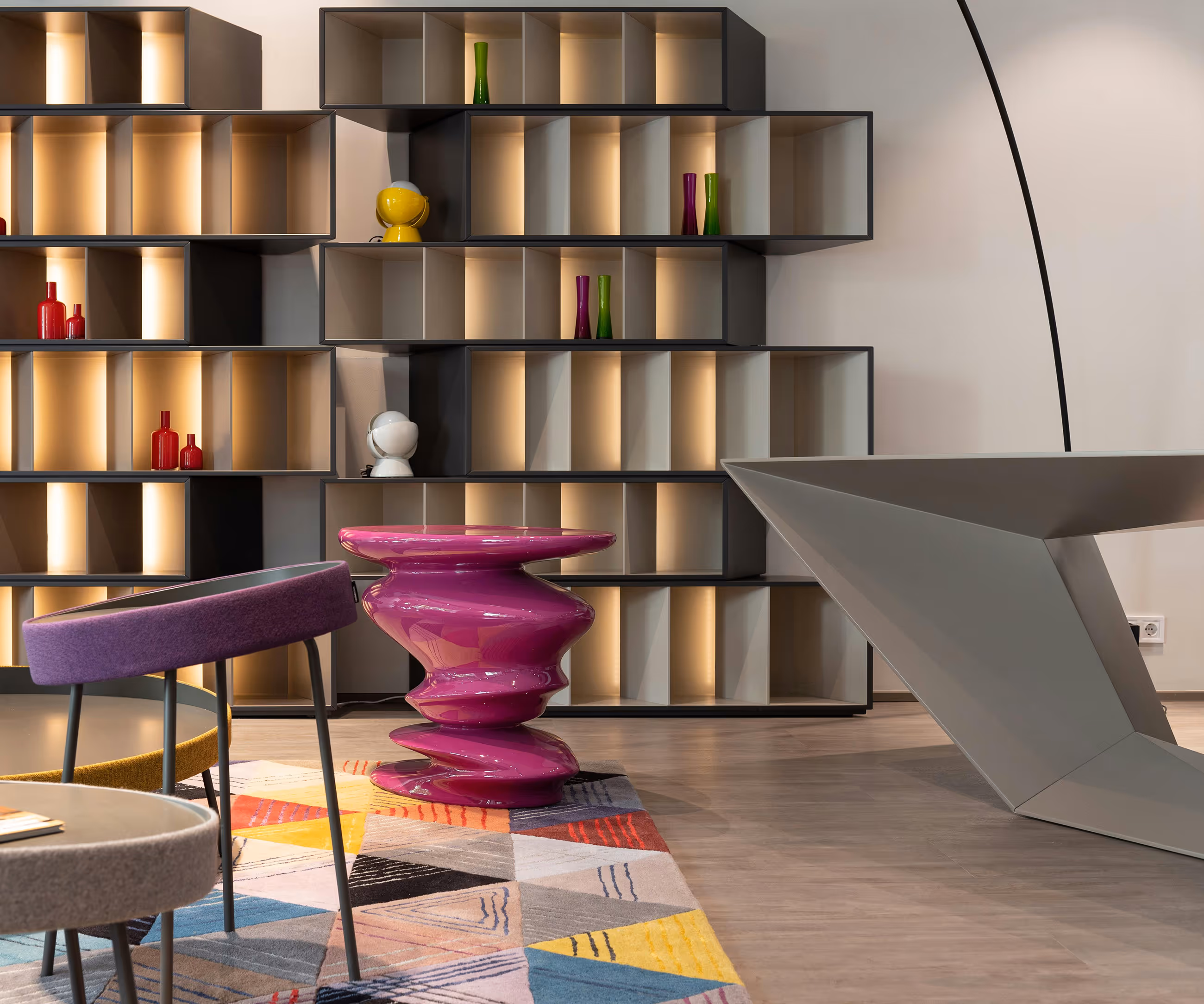 Modern shelves, purple sculptural table, and geometric desk
