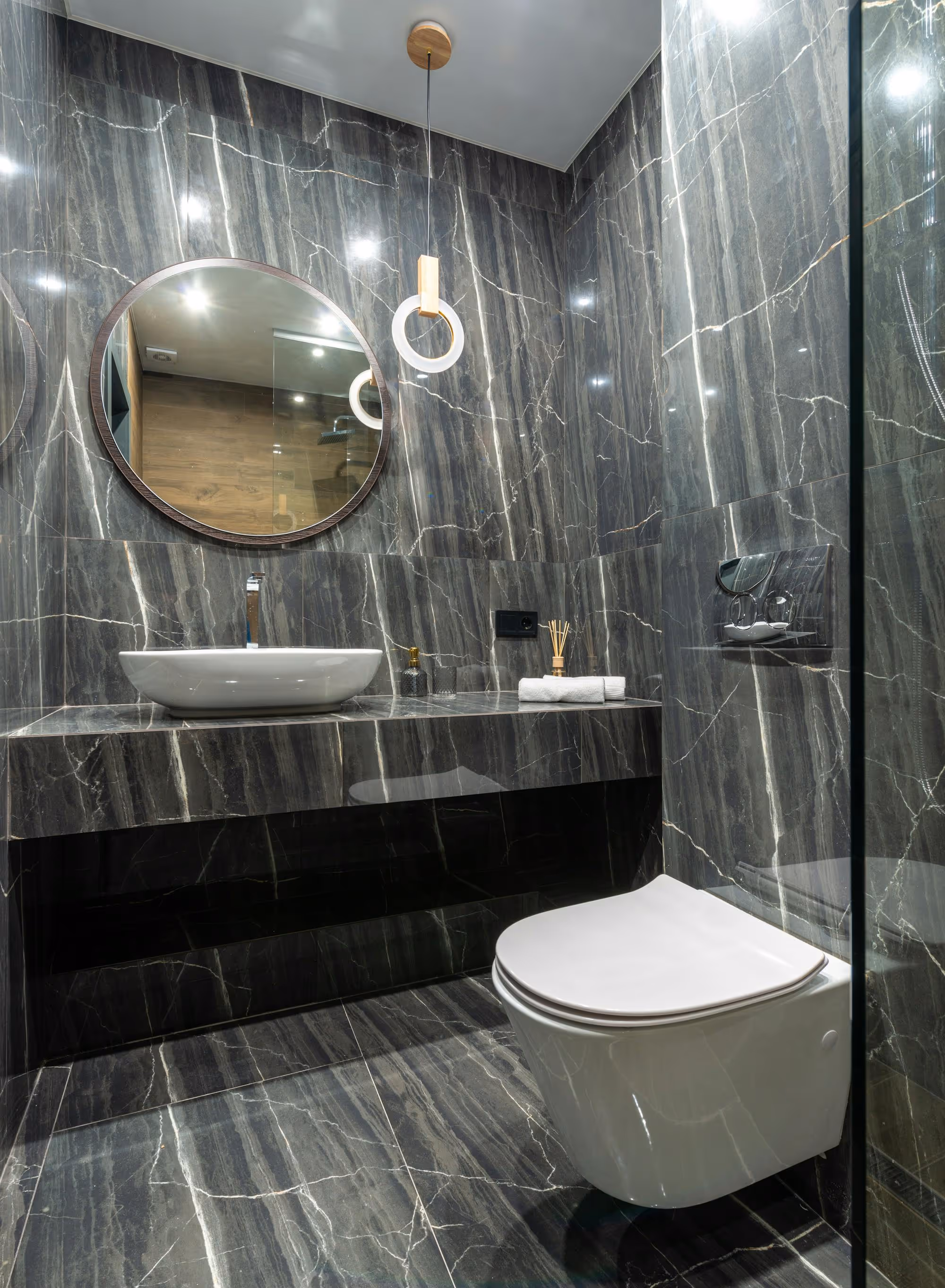 Grey marble bathroom with round mirror and floating sink