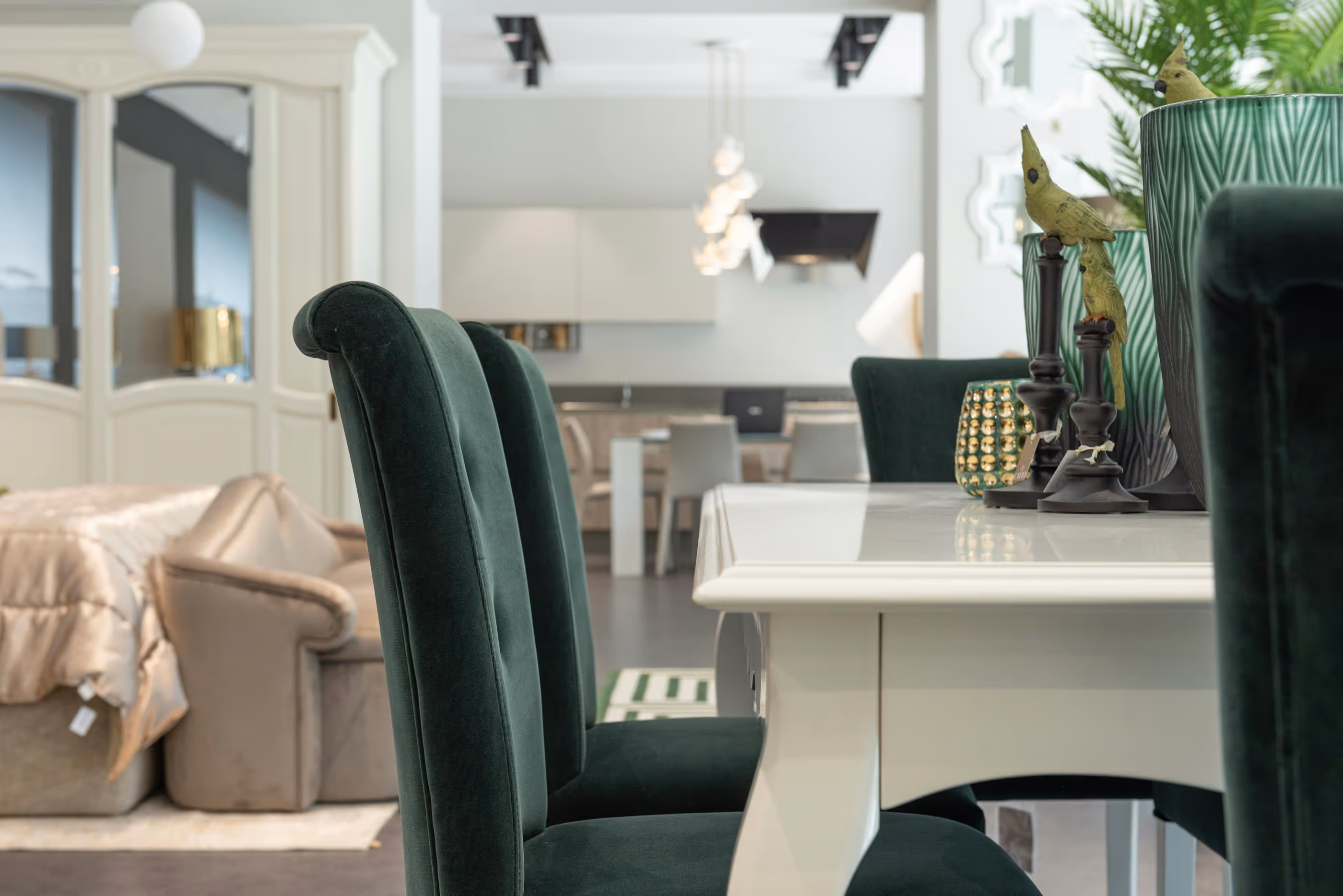 Close-up of dark green velvet dining chairs around a white table with decorative accents
