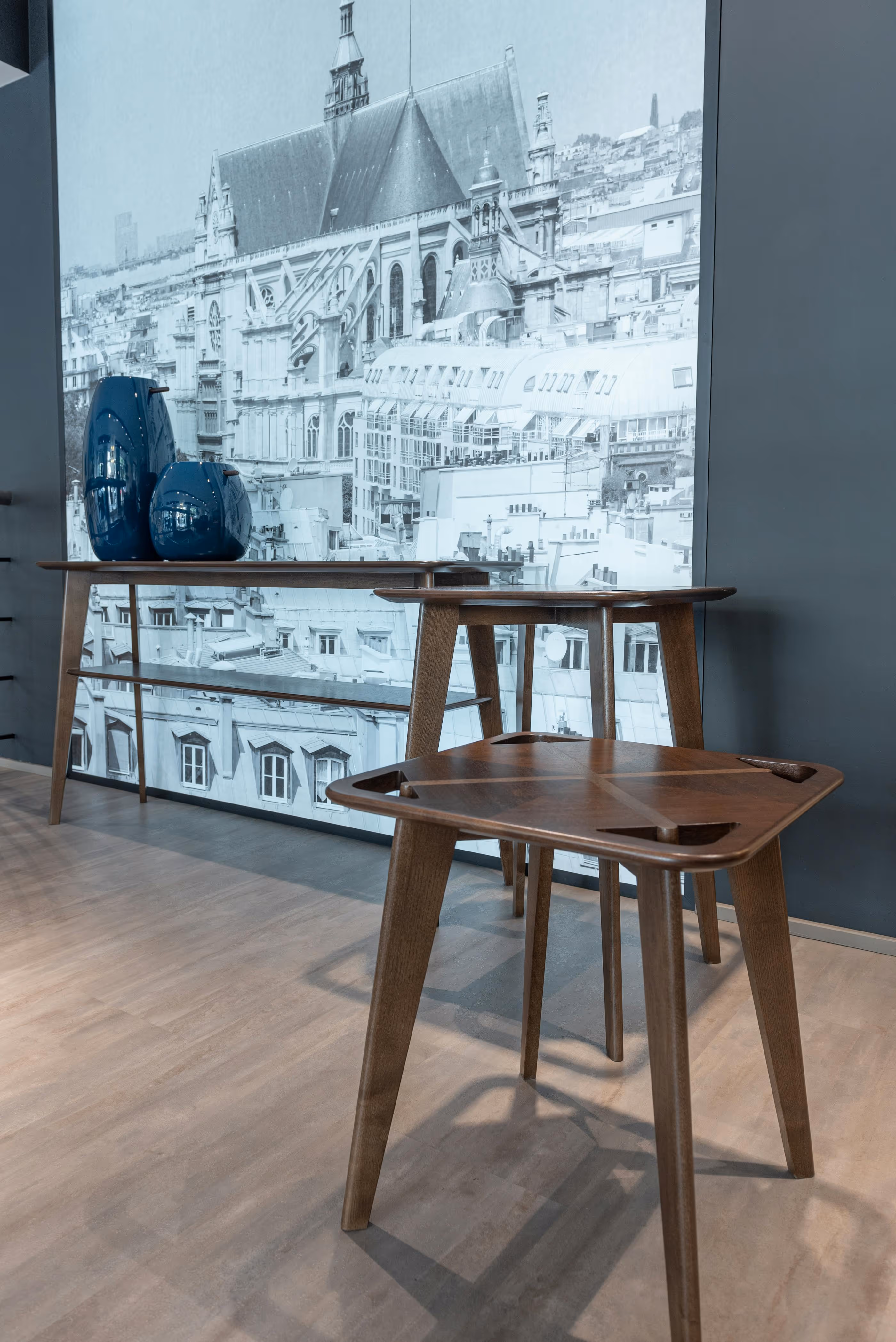 Wood tables with blue vases against a mural wall