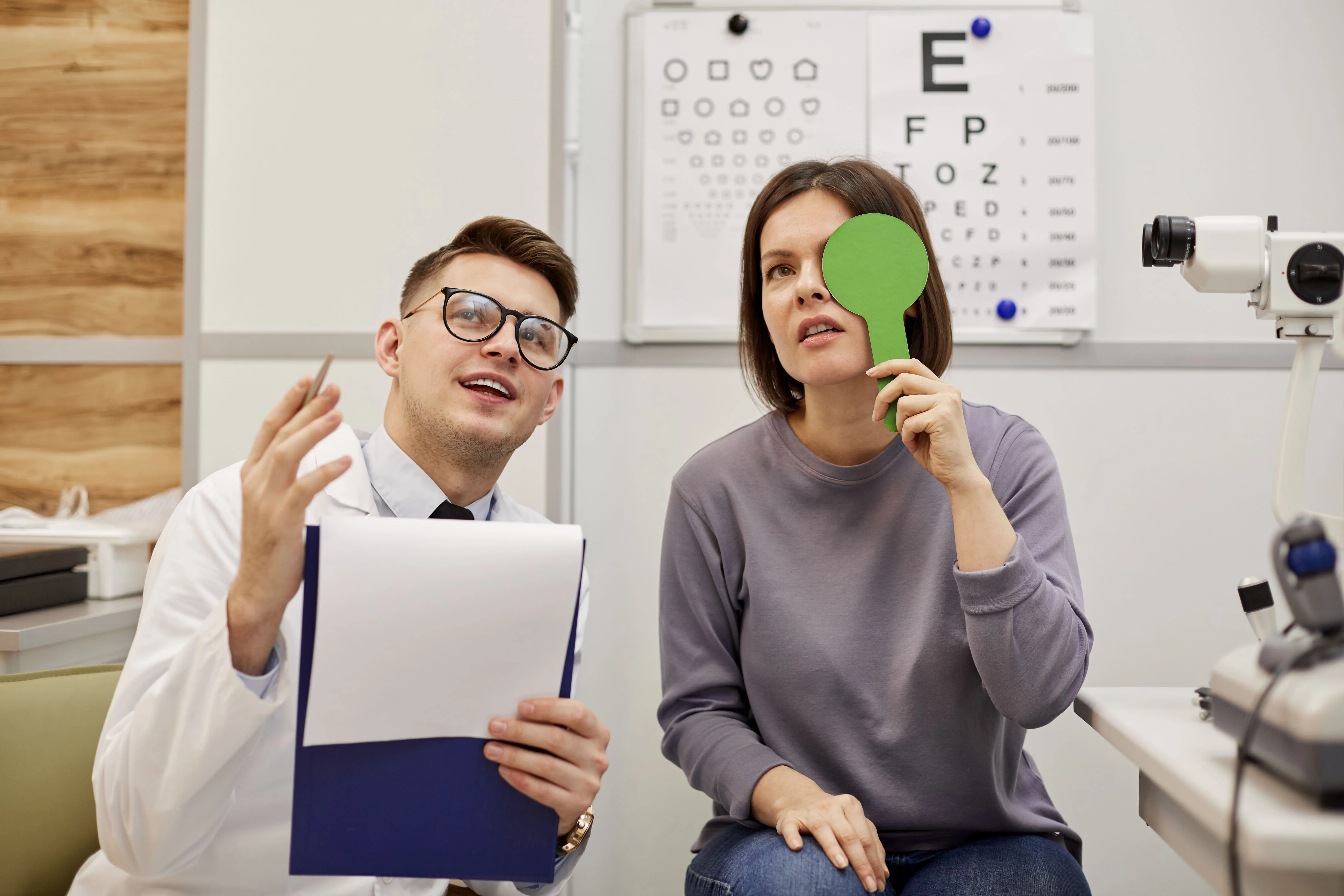 Patient getting eye exam with doctor in medical office with eye chart