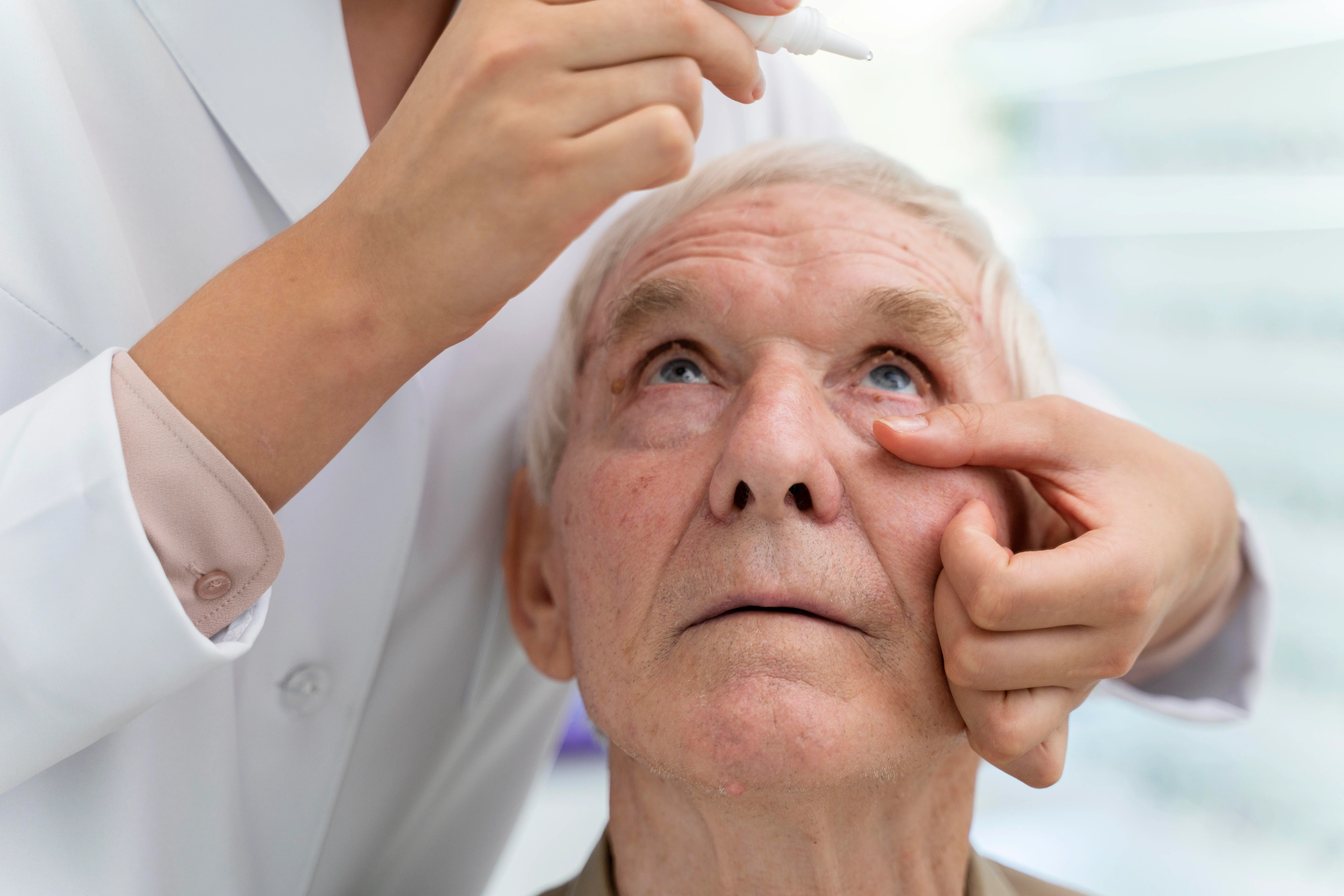 Healthcare professional examining elderly patient's eye during medical checkup
