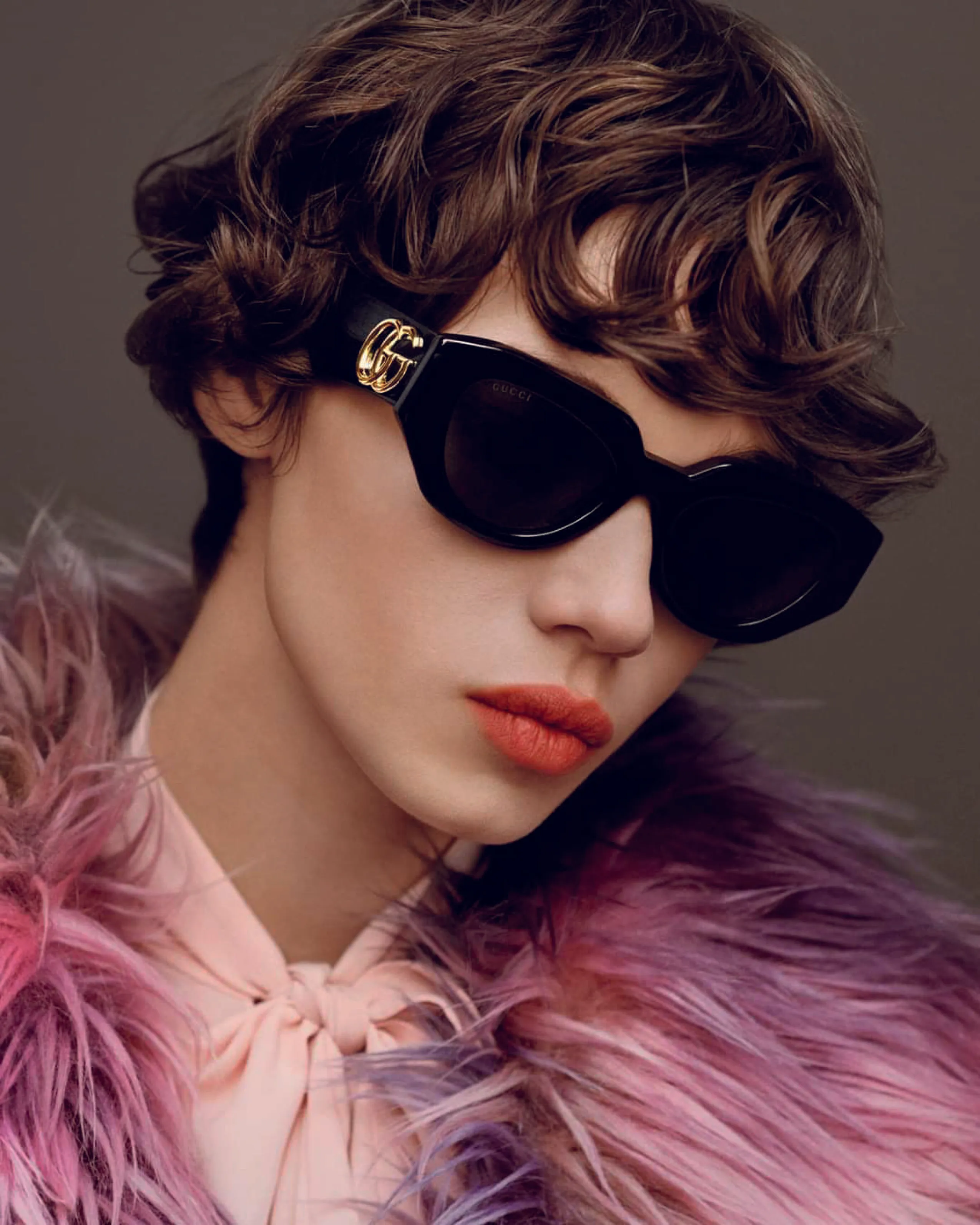 Stylish individual in black sunglasses and pink feathered coat