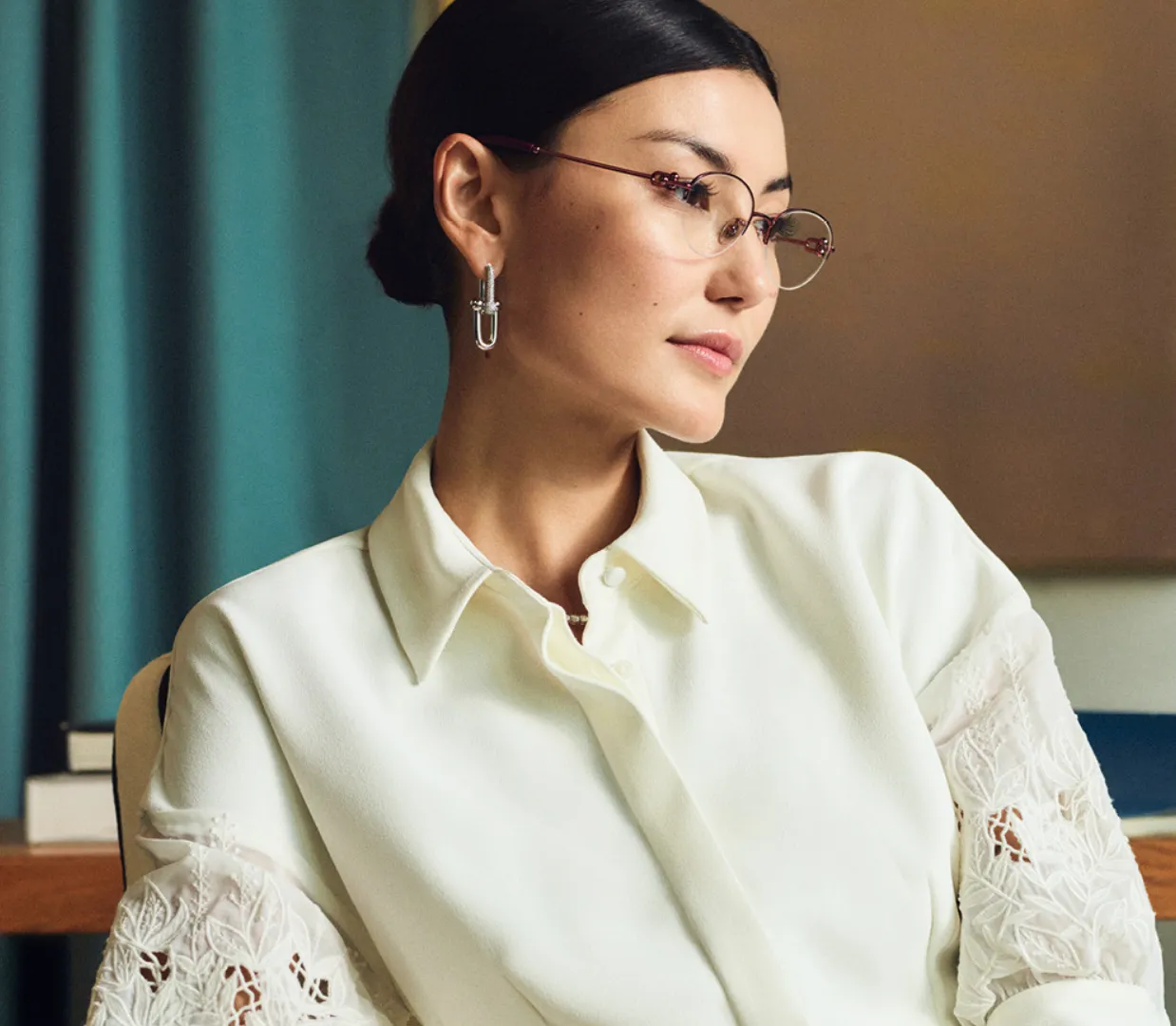 Professional woman in white blouse with lace sleeves and glasses