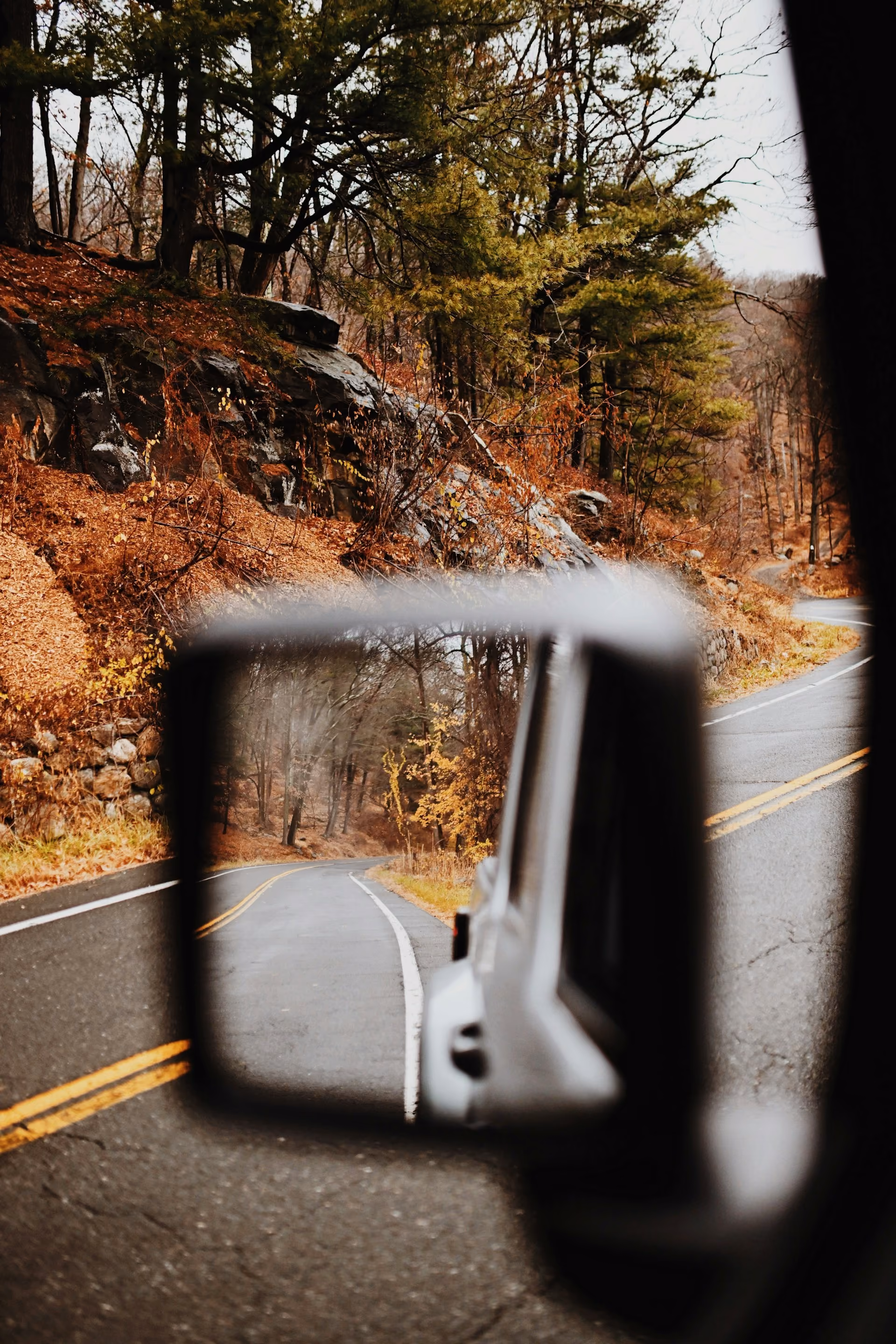 A mountain road in a car mirror — photography by Blake Wisz