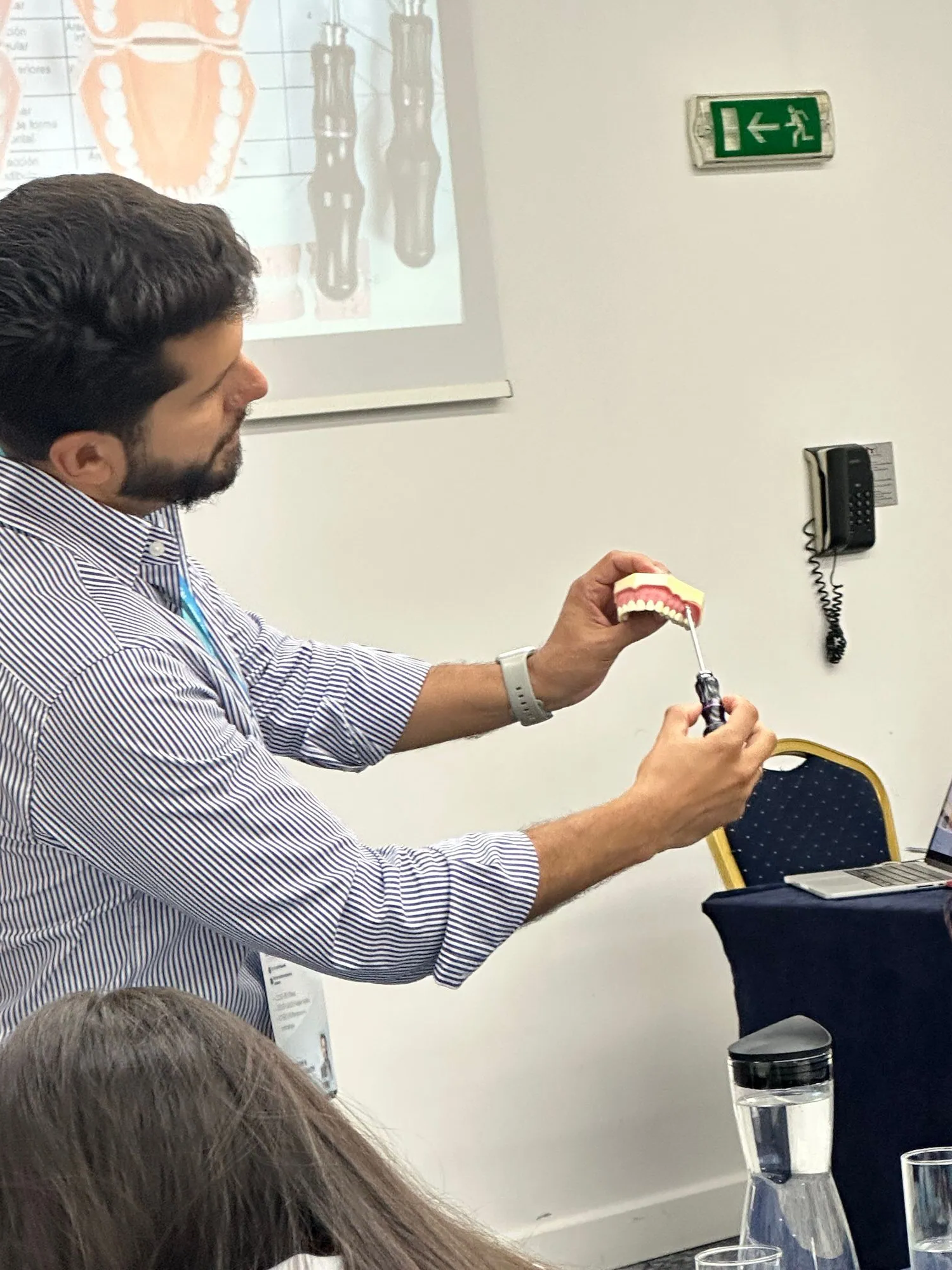 Дентален обучител демонстрира модел на зъби пред участници.