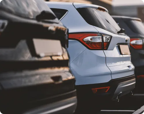 Rear view of parked cars lined up outdoors focusing on a white SUV in the center.