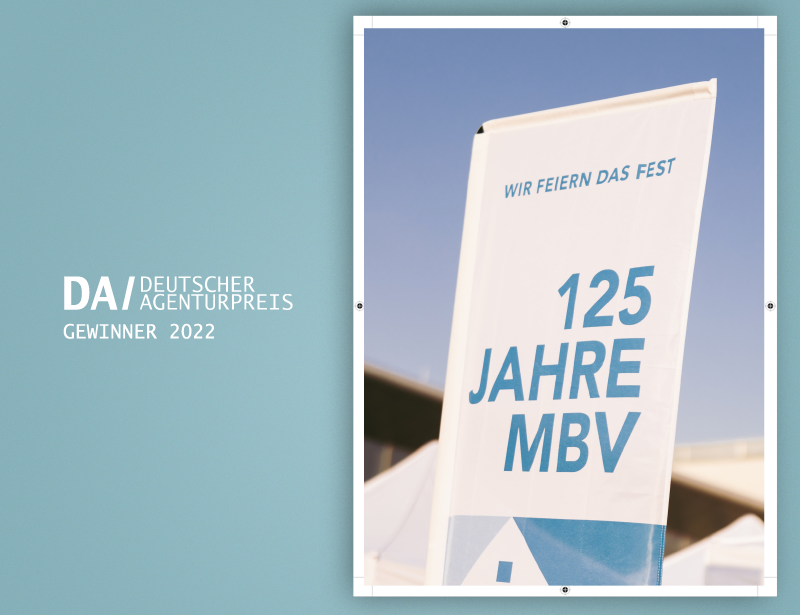 Banner celebrating 125 years of MBV with the text 'Wir feiern das Fest' against a clear sky background, alongside the Deutscher Agenturpreis 2022 winner logo.
