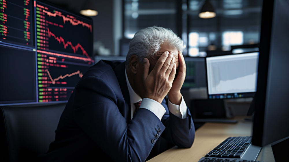 Business owner looking at financial reports while dealing with computer downtime and technology issues affecting daily operations.