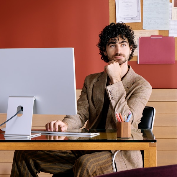 Man sitting at desk with computer, resting chin