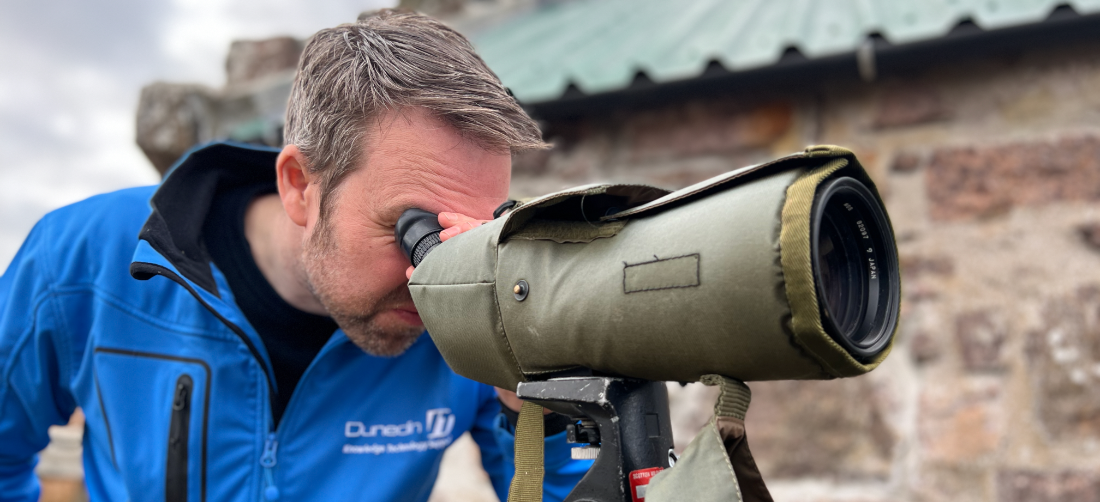 Jamie looking through a spotting bird telescope out to see from Handa Island
