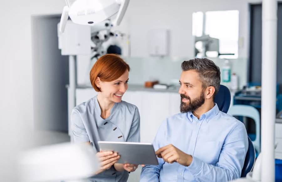 A man and a woman are looking at a tablet in a dentist surgery.