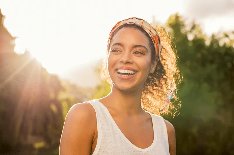 A woman with a bandanna on her head smiles at the camera.