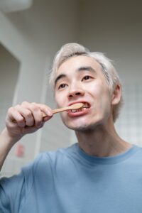 Blonde man brushing his teeth to improve oral health