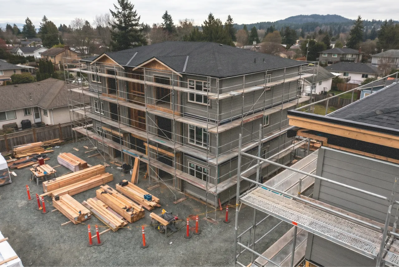 Three-story residential building under construction with scaffolding and wood materials outside. Edda Construction.