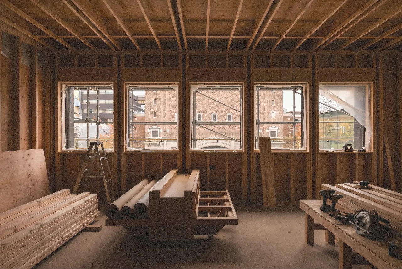 Interior of a wooden-framed room under construction with wood planks and power tools on benches. Edda Construction.