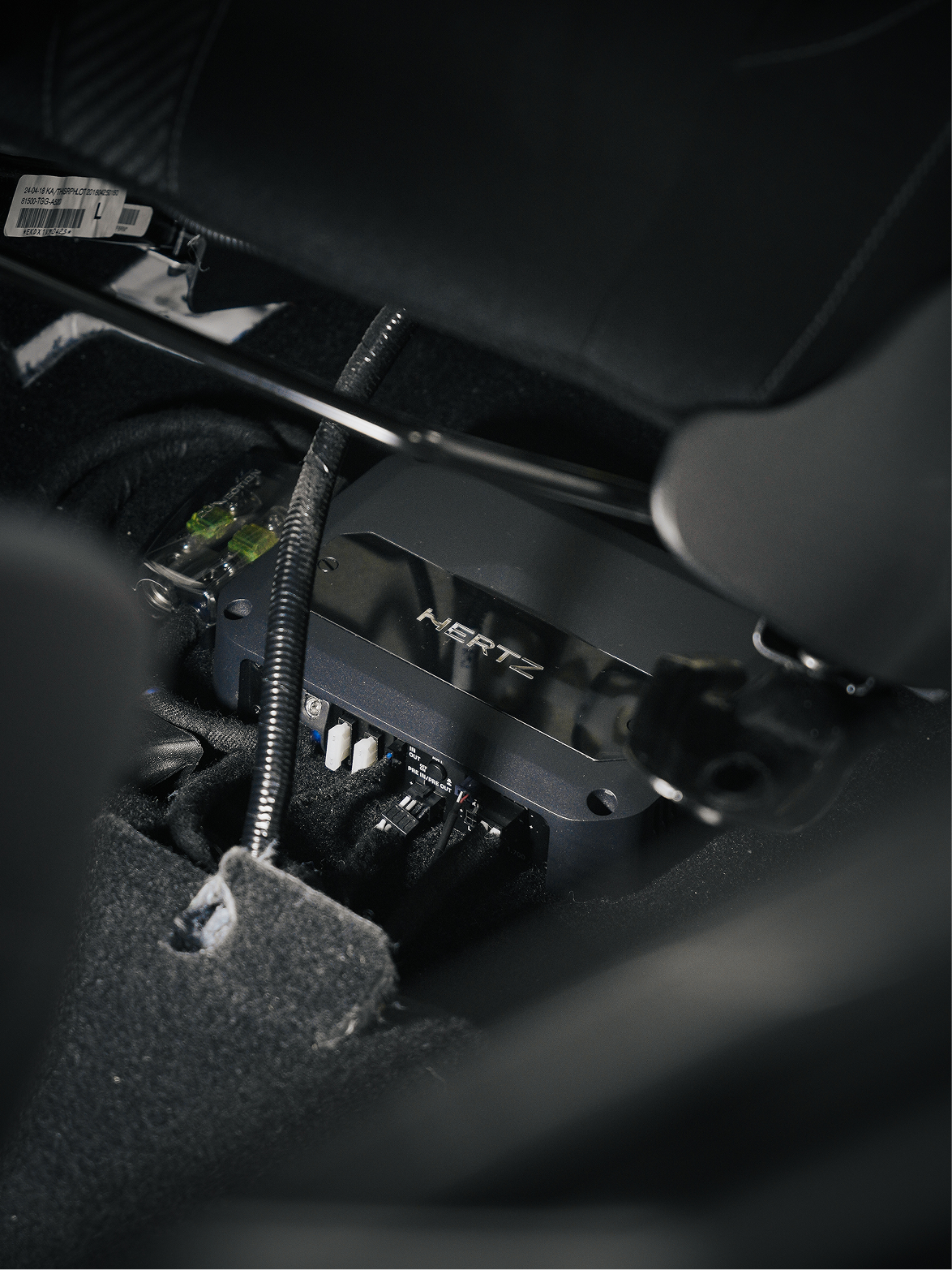 Hertz DSP installed under a car seat with clean hidden wiring and connections.