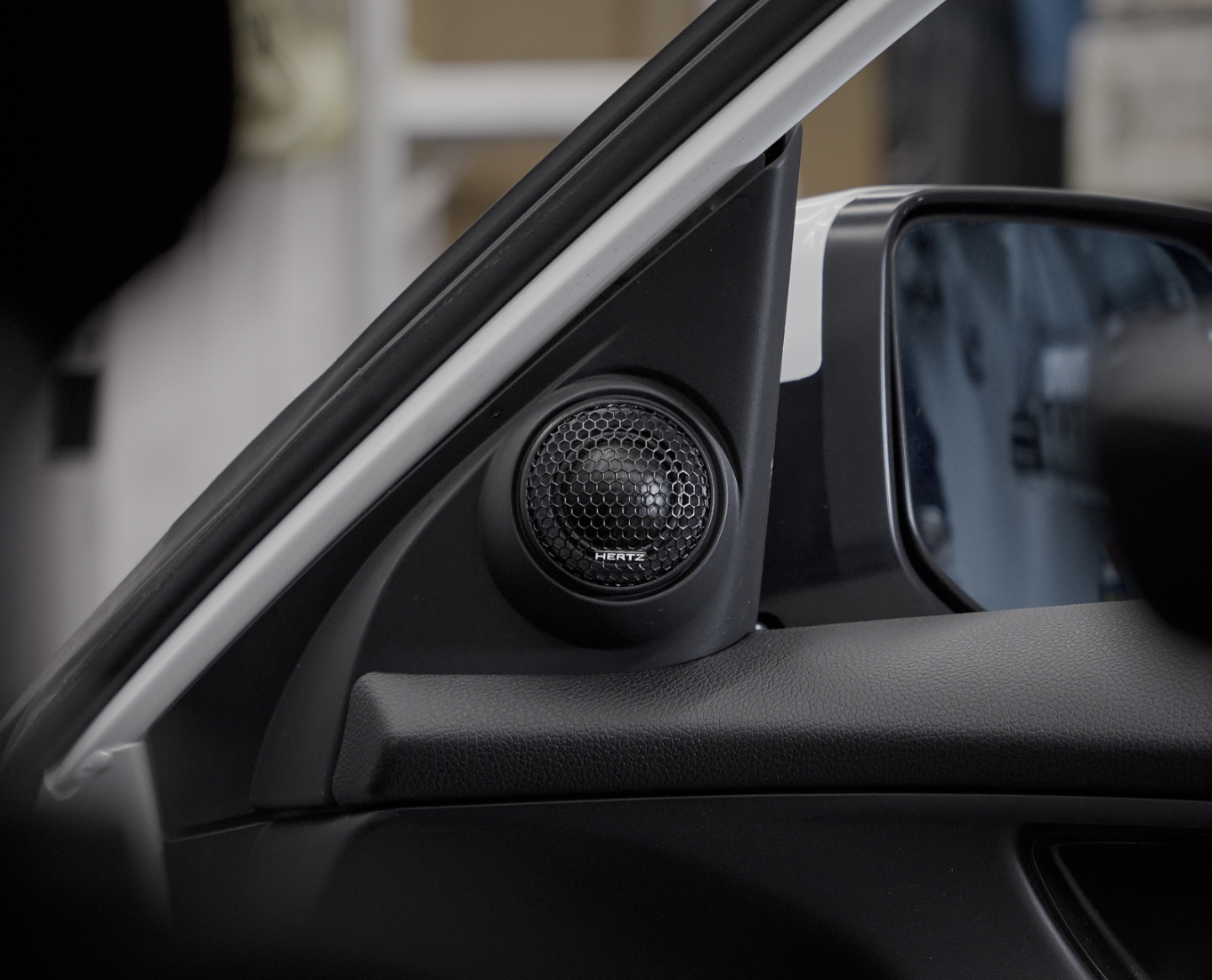 Close-up of a Hertz Tweeters and side mirror on the interior driver’s side door.