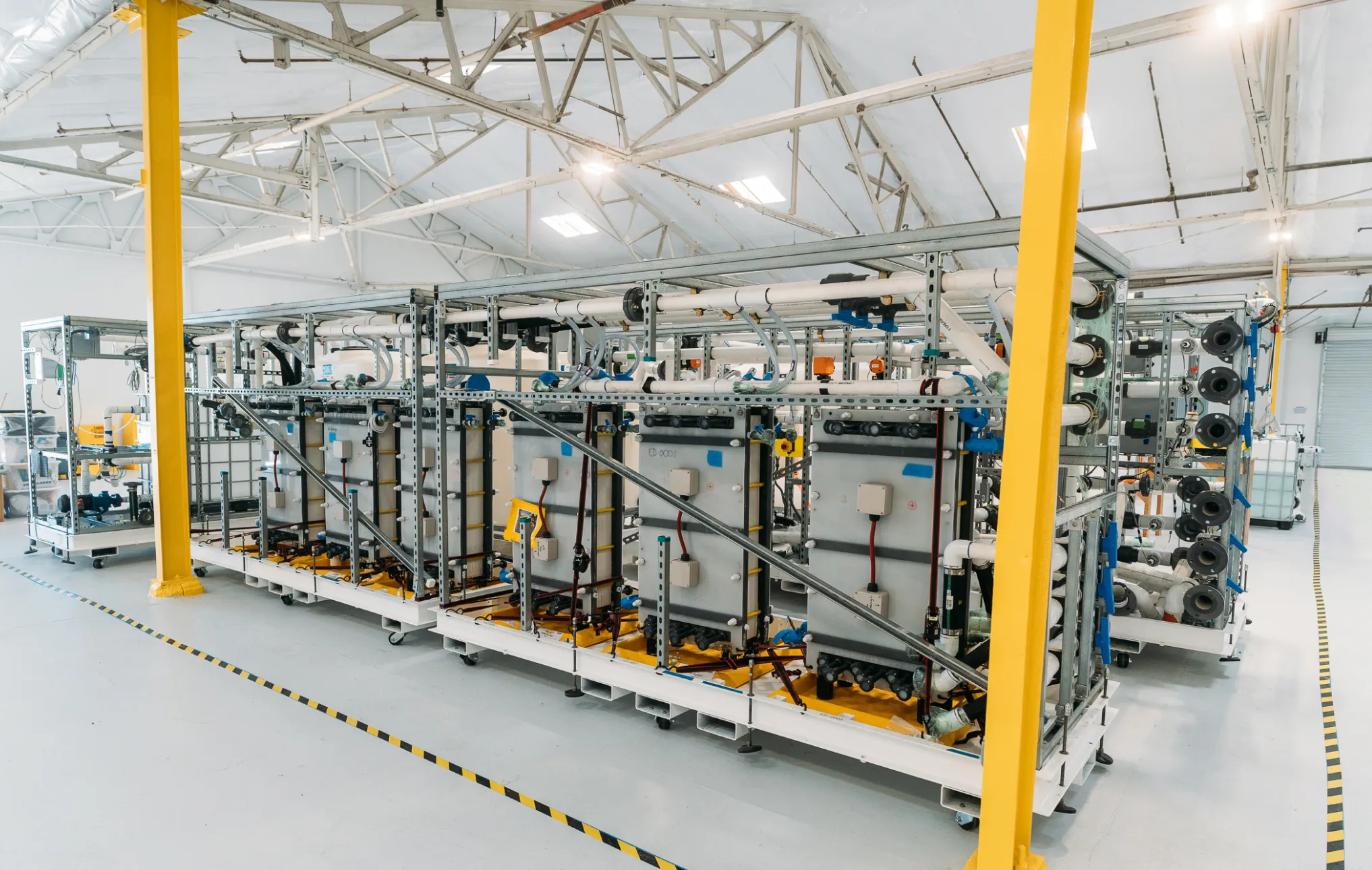 Industrial membrane filtration system with multiple modules and connected piping in a clean factory setting.