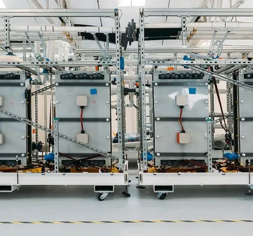 Industrial setup of large membrane stacks with metal framing, wiring, and connected pipes in a spacious facility.