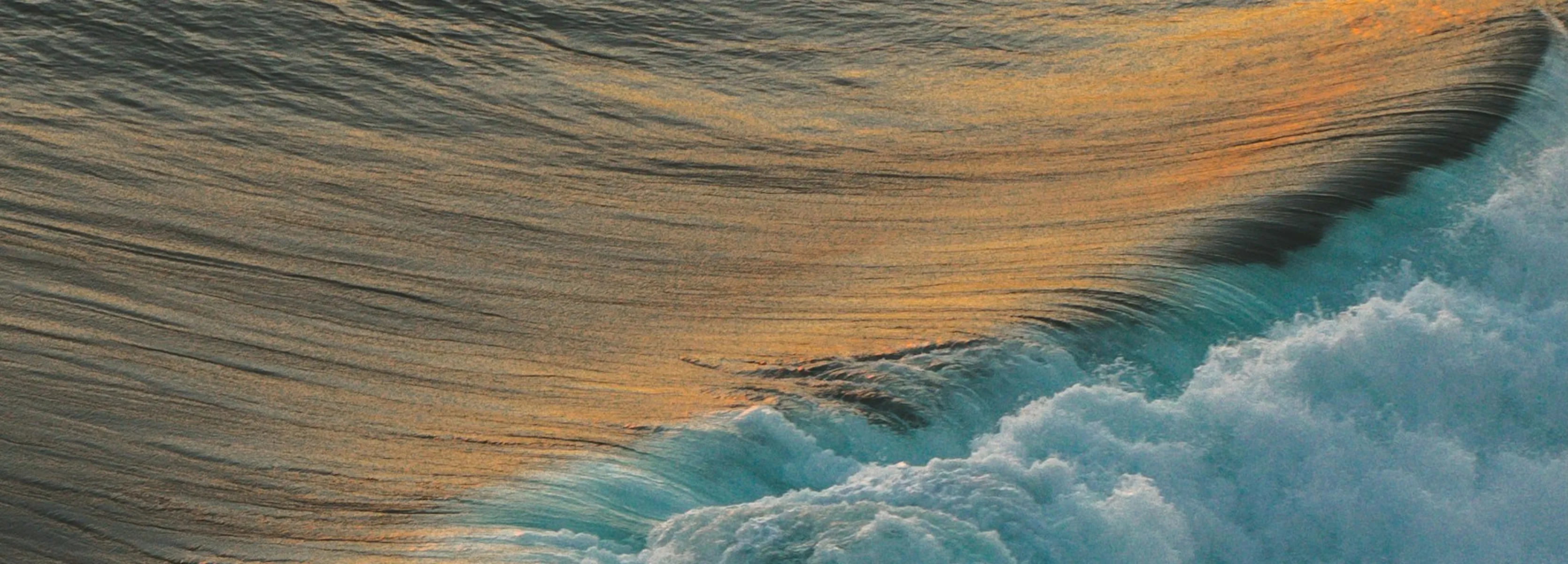 Ocean waves rolling and frothing with sunlight reflecting on the water surface.