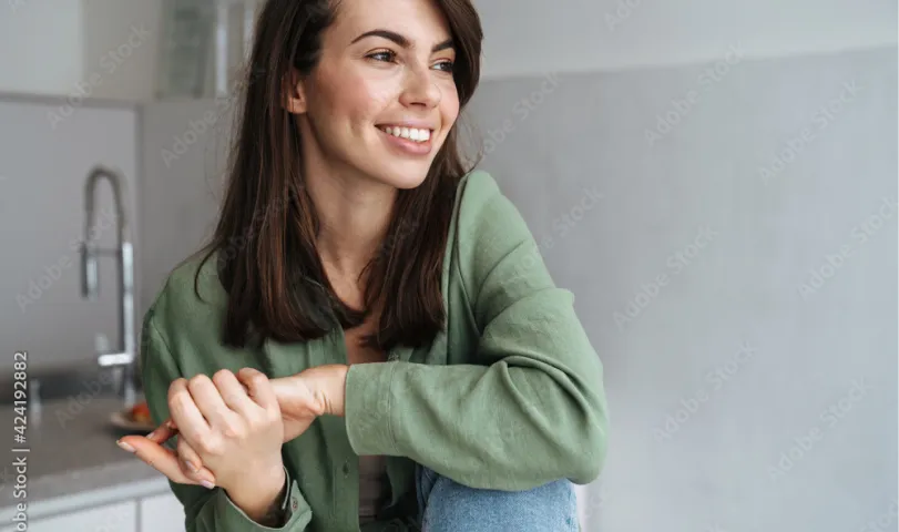 A woman sitting in a kitchen with a smile on her face.