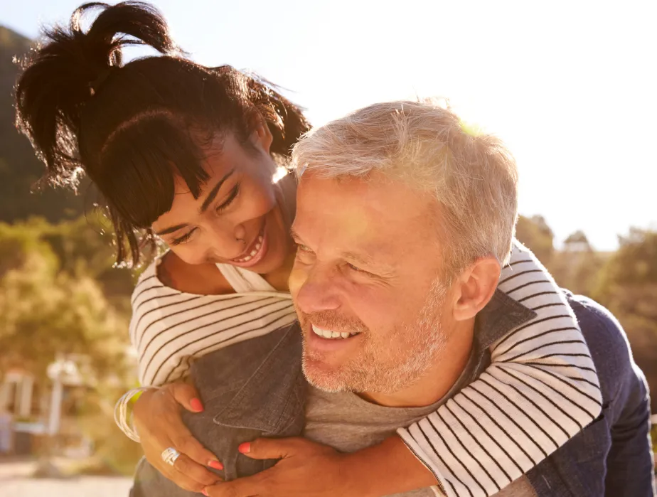 An older man is hugging a younger woman.
