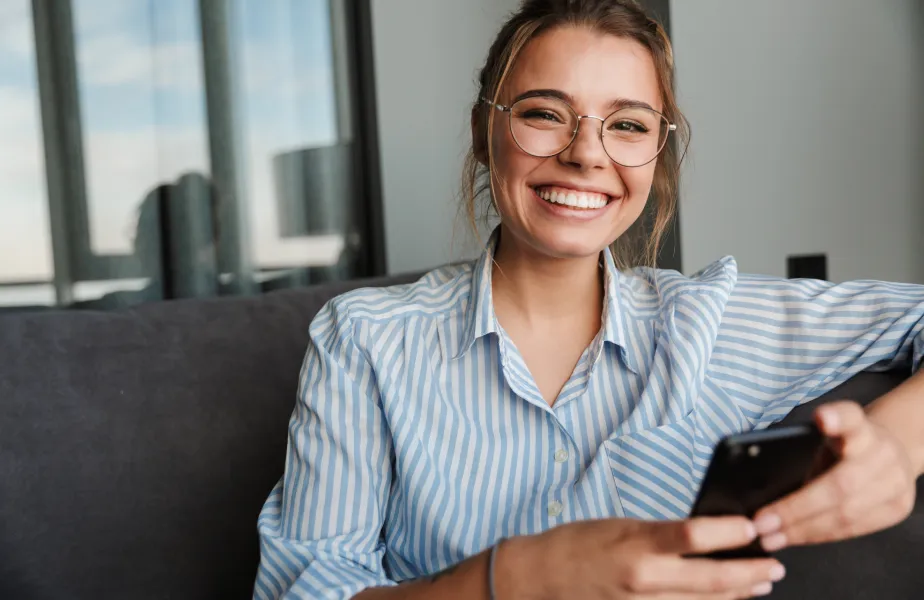 A woman sitting on a couch holding a cell phone.